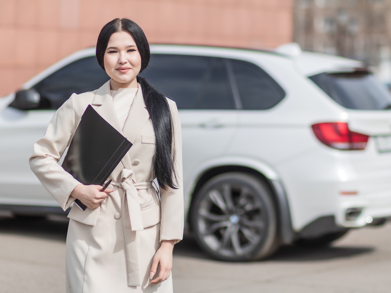 en kvinna med långt svart hår står framför en vit bil