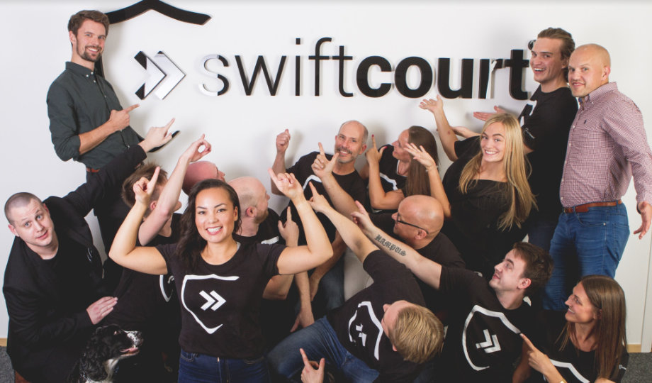Swiftcourt anställda som pekar mot en Swiftcourt logga