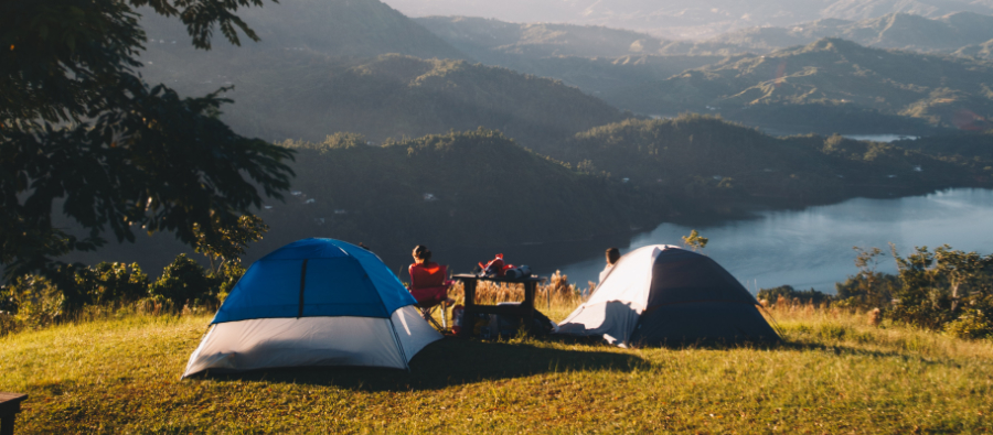 Två tält på gräsmatta, med berg och vatten som utsikt